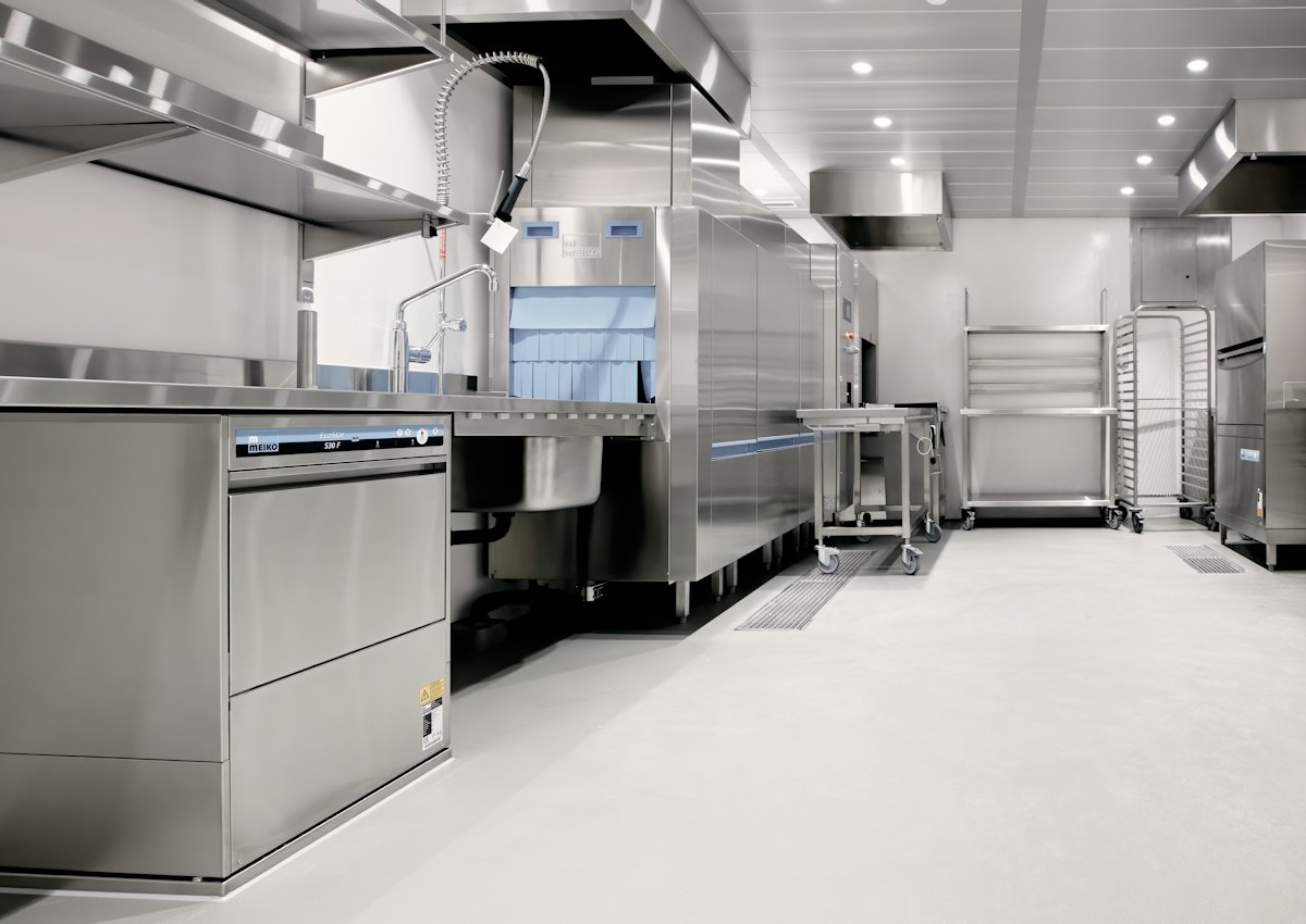 An empty commercial kitchen with stainless steel equipment